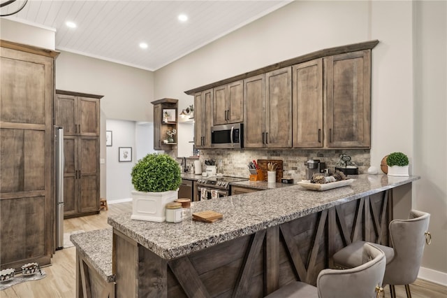 kitchen featuring appliances with stainless steel finishes, light hardwood / wood-style floors, and light stone counters