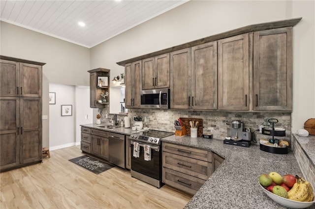 kitchen featuring backsplash, stainless steel appliances, crown molding, light hardwood / wood-style flooring, and dark stone countertops