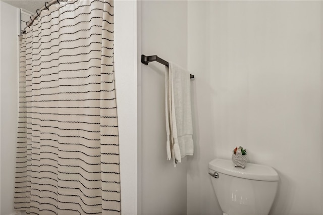 bathroom featuring toilet and curtained shower