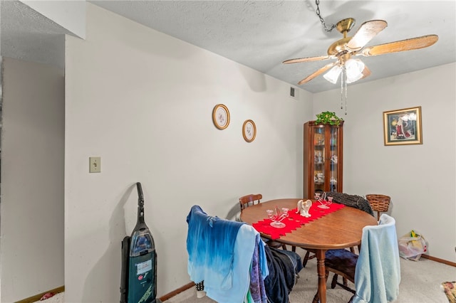 carpeted dining area featuring a textured ceiling and ceiling fan