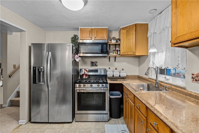 kitchen with sink, light tile patterned floors, a textured ceiling, and appliances with stainless steel finishes