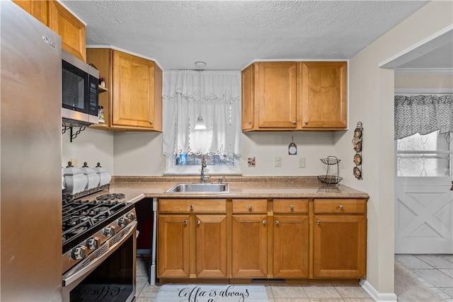 kitchen with a wealth of natural light, light tile patterned flooring, sink, and appliances with stainless steel finishes