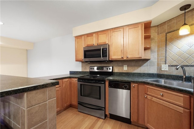 kitchen featuring sink, hanging light fixtures, tasteful backsplash, appliances with stainless steel finishes, and light wood-type flooring