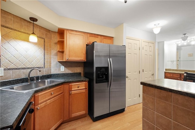 kitchen with stainless steel fridge, backsplash, sink, pendant lighting, and light hardwood / wood-style flooring