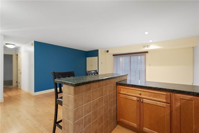 kitchen featuring a kitchen bar, light wood-type flooring, and kitchen peninsula