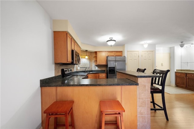 kitchen featuring a breakfast bar, stainless steel appliances, kitchen peninsula, and sink