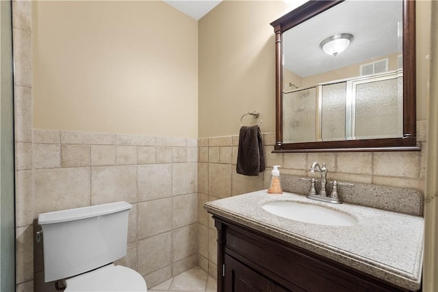 bathroom with walk in shower, vanity, tile walls, and toilet