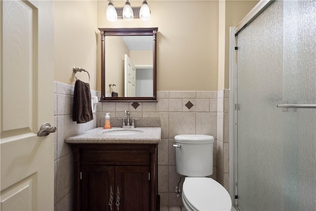 bathroom featuring vanity, toilet, an enclosed shower, and tile walls