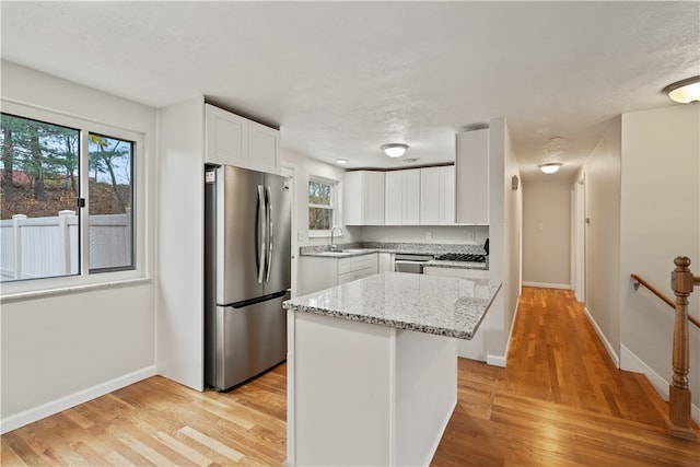 kitchen featuring appliances with stainless steel finishes, a center island, light hardwood / wood-style flooring, and a wealth of natural light