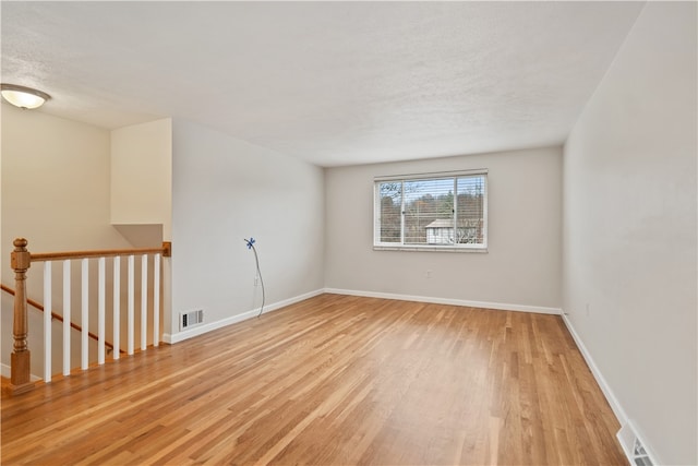 empty room featuring a textured ceiling and light hardwood / wood-style flooring