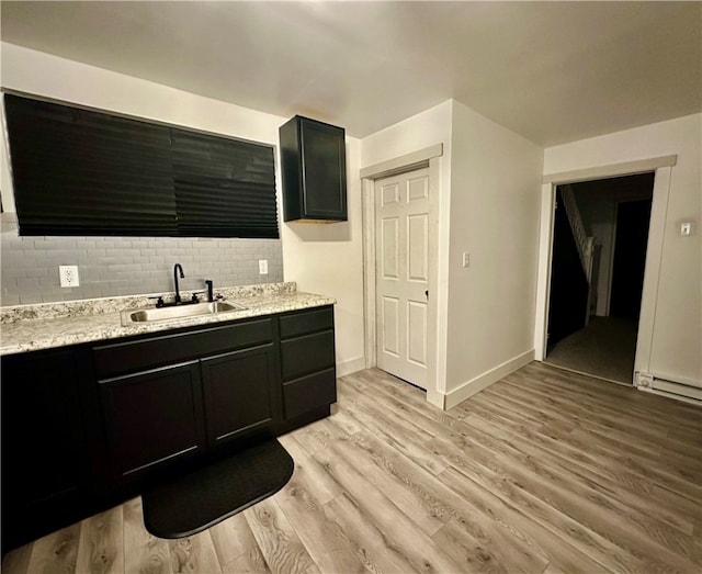 bathroom with sink, decorative backsplash, wood-type flooring, and a baseboard radiator