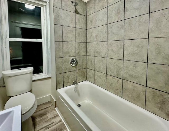 bathroom featuring wood-type flooring, toilet, and tiled shower / bath combo