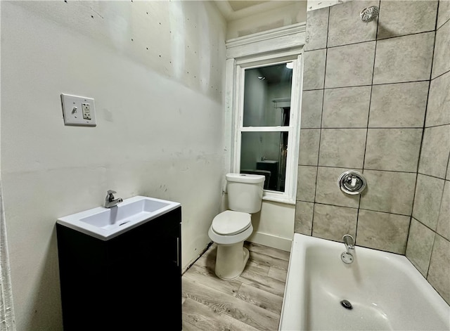 bathroom featuring a tub to relax in, toilet, hardwood / wood-style floors, and vanity