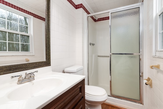 bathroom featuring vanity, crown molding, tile walls, toilet, and a shower with shower door