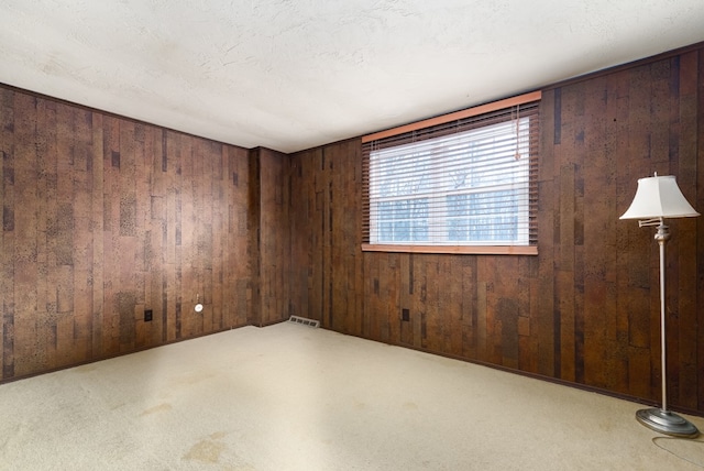 carpeted spare room with wooden walls