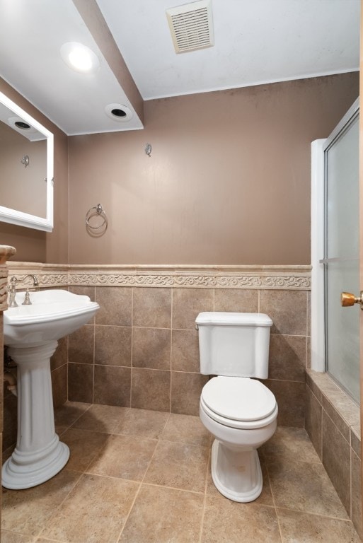 bathroom with toilet, tile walls, and walk in shower