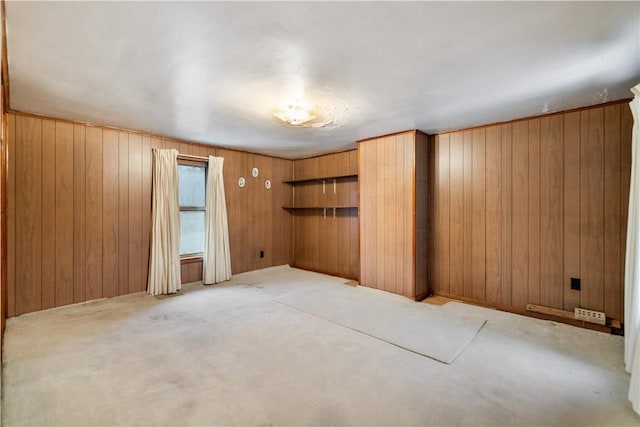 carpeted spare room featuring wood walls