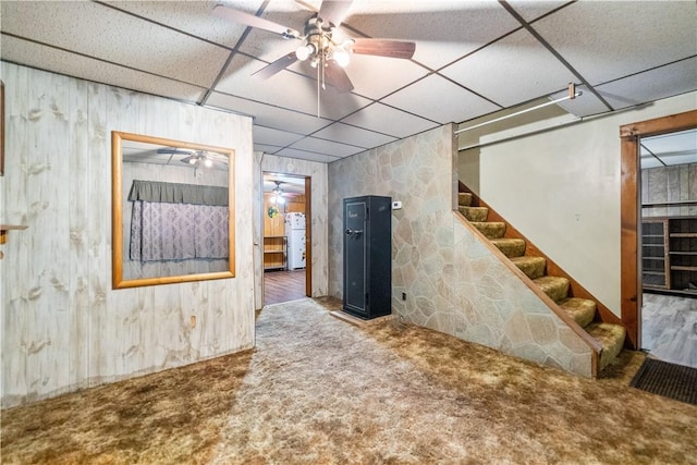 basement featuring a paneled ceiling, carpet floors, and white fridge