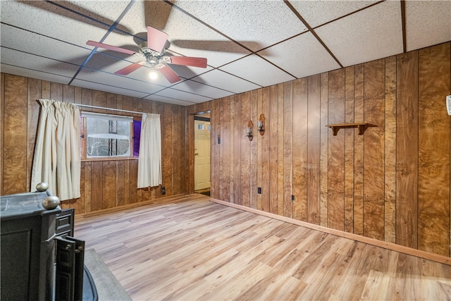 spare room with a paneled ceiling, wood walls, and hardwood / wood-style flooring