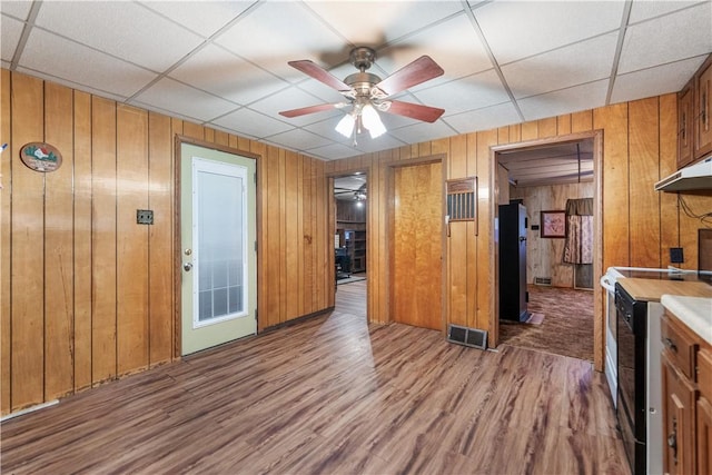 kitchen with black / electric stove, ceiling fan, wooden walls, and hardwood / wood-style flooring