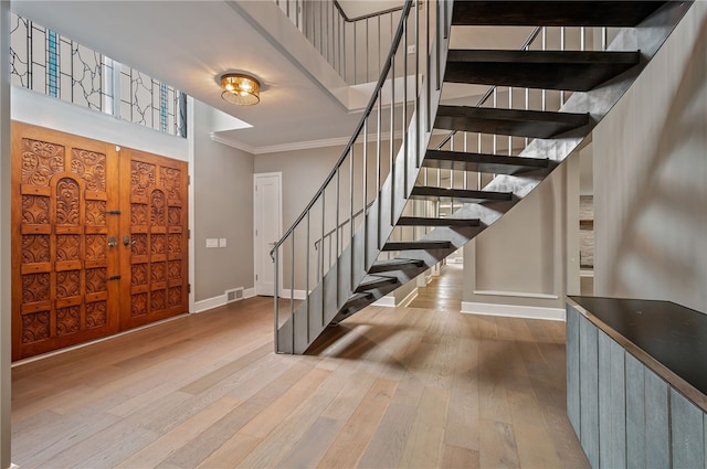 entrance foyer with light hardwood / wood-style floors, crown molding, and a high ceiling