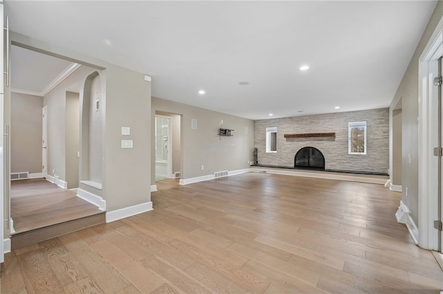 unfurnished living room with a fireplace, crown molding, and light hardwood / wood-style flooring