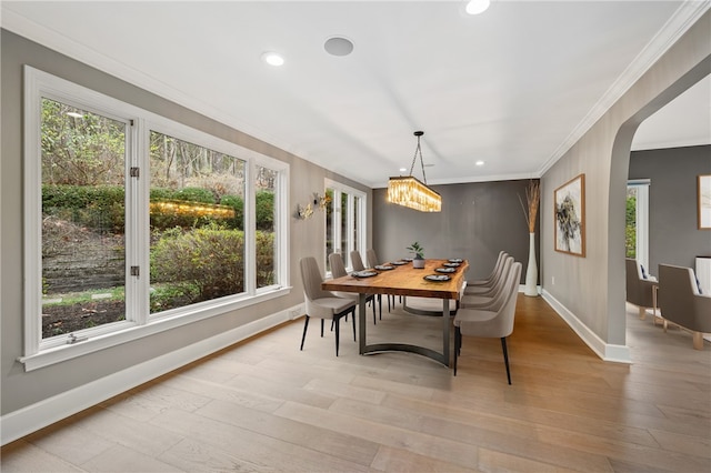 dining room featuring light wood-type flooring, crown molding, and an inviting chandelier