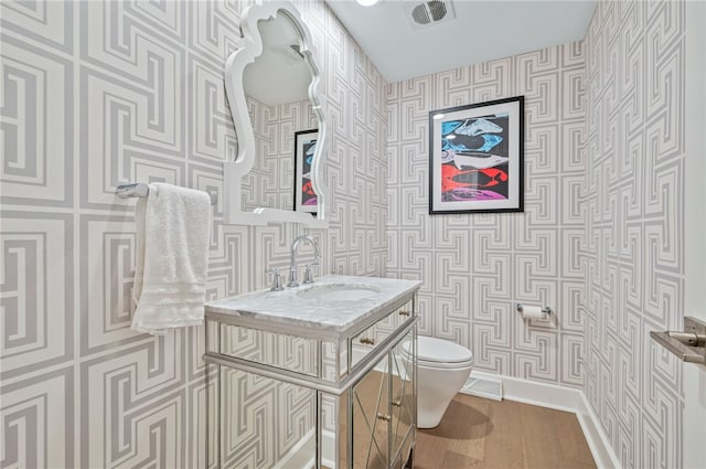 bathroom with toilet, hardwood / wood-style floors, and sink