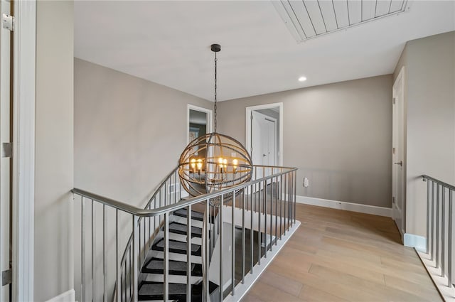 staircase with wood-type flooring and an inviting chandelier