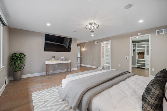 bedroom featuring a walk in closet, a closet, and light hardwood / wood-style floors