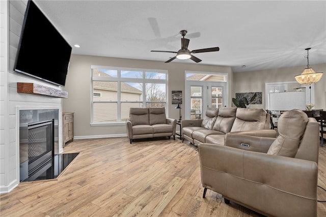 living room with ceiling fan with notable chandelier and light wood-type flooring