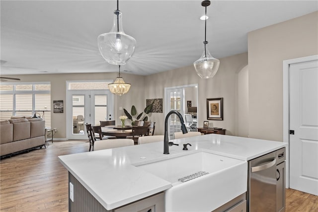 kitchen featuring a kitchen island with sink, decorative light fixtures, and light wood-type flooring