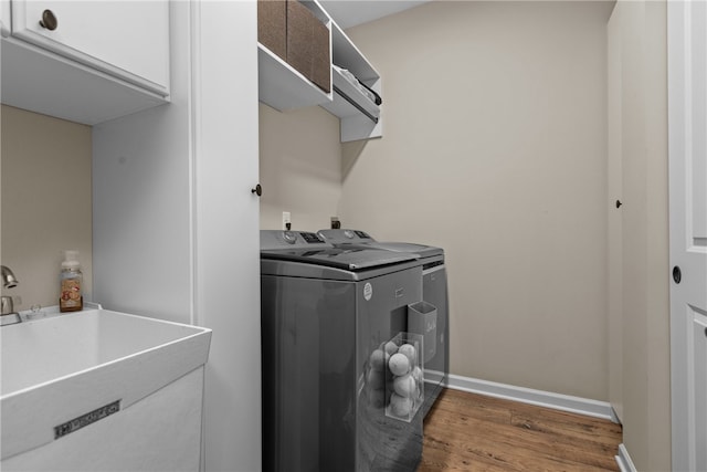 clothes washing area with cabinets, dark hardwood / wood-style flooring, washer and dryer, and sink