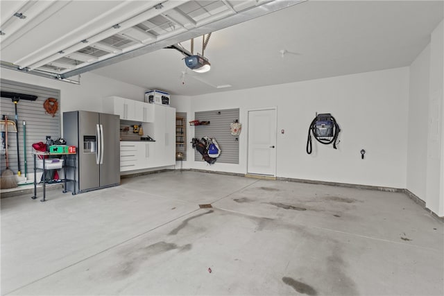 garage featuring stainless steel refrigerator with ice dispenser and a garage door opener