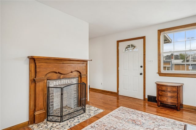 foyer entrance with a fireplace and light hardwood / wood-style flooring