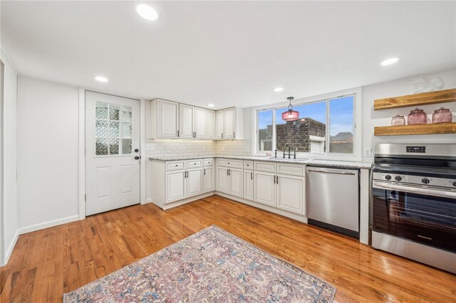 kitchen featuring backsplash, stainless steel appliances, white cabinetry, and light hardwood / wood-style flooring