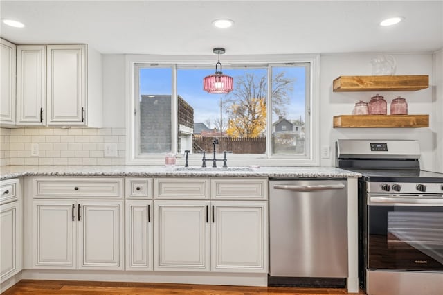 kitchen with pendant lighting, sink, decorative backsplash, light stone counters, and stainless steel appliances