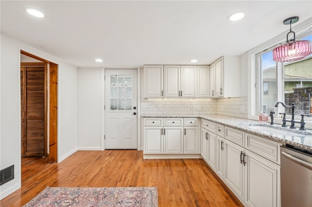 kitchen with dishwasher, sink, hanging light fixtures, light hardwood / wood-style floors, and white cabinets