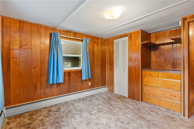 unfurnished bedroom with a textured ceiling, a baseboard radiator, light colored carpet, and wood walls