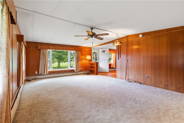 unfurnished living room with carpet, baseboard heating, wooden walls, and ceiling fan