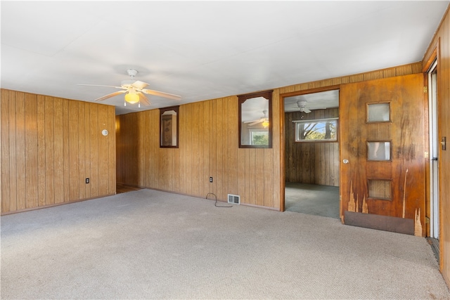 spare room with light carpet, ceiling fan, and wooden walls