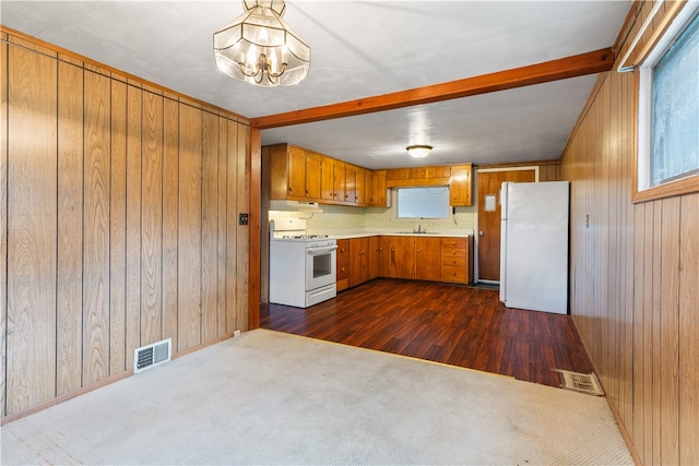 kitchen with sink, an inviting chandelier, dark hardwood / wood-style flooring, wood walls, and white appliances