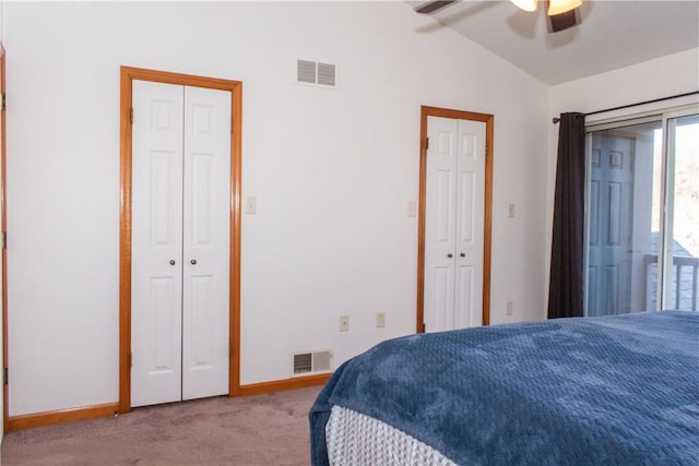 bedroom featuring multiple closets, light colored carpet, ceiling fan, and lofted ceiling