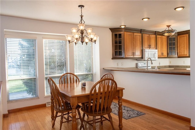 dining space featuring light wood-type flooring and an inviting chandelier