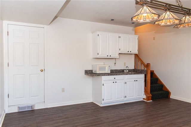 kitchen with white cabinets, decorative light fixtures, dark hardwood / wood-style floors, and sink