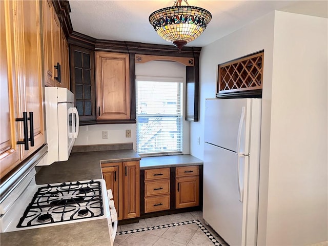 kitchen featuring light tile patterned floors, white refrigerator, hanging light fixtures, and range