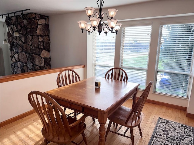 dining area with light hardwood / wood-style flooring and a notable chandelier