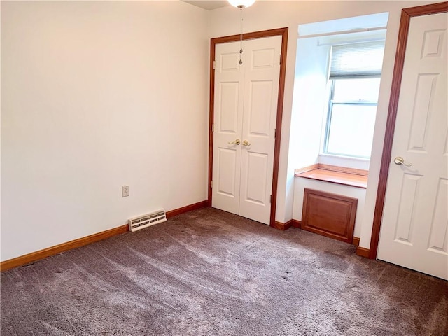 unfurnished bedroom with dark colored carpet and a closet