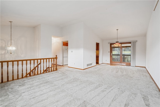 empty room featuring carpet floors, vaulted ceiling, and a notable chandelier