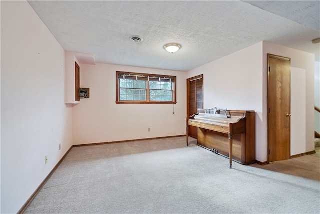 empty room with a textured ceiling and light colored carpet